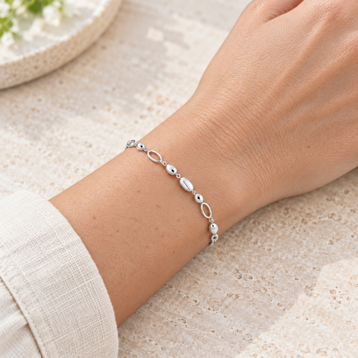 Bracelet gouttes et ovales polis — poignet de femme à peau claire, sans visage